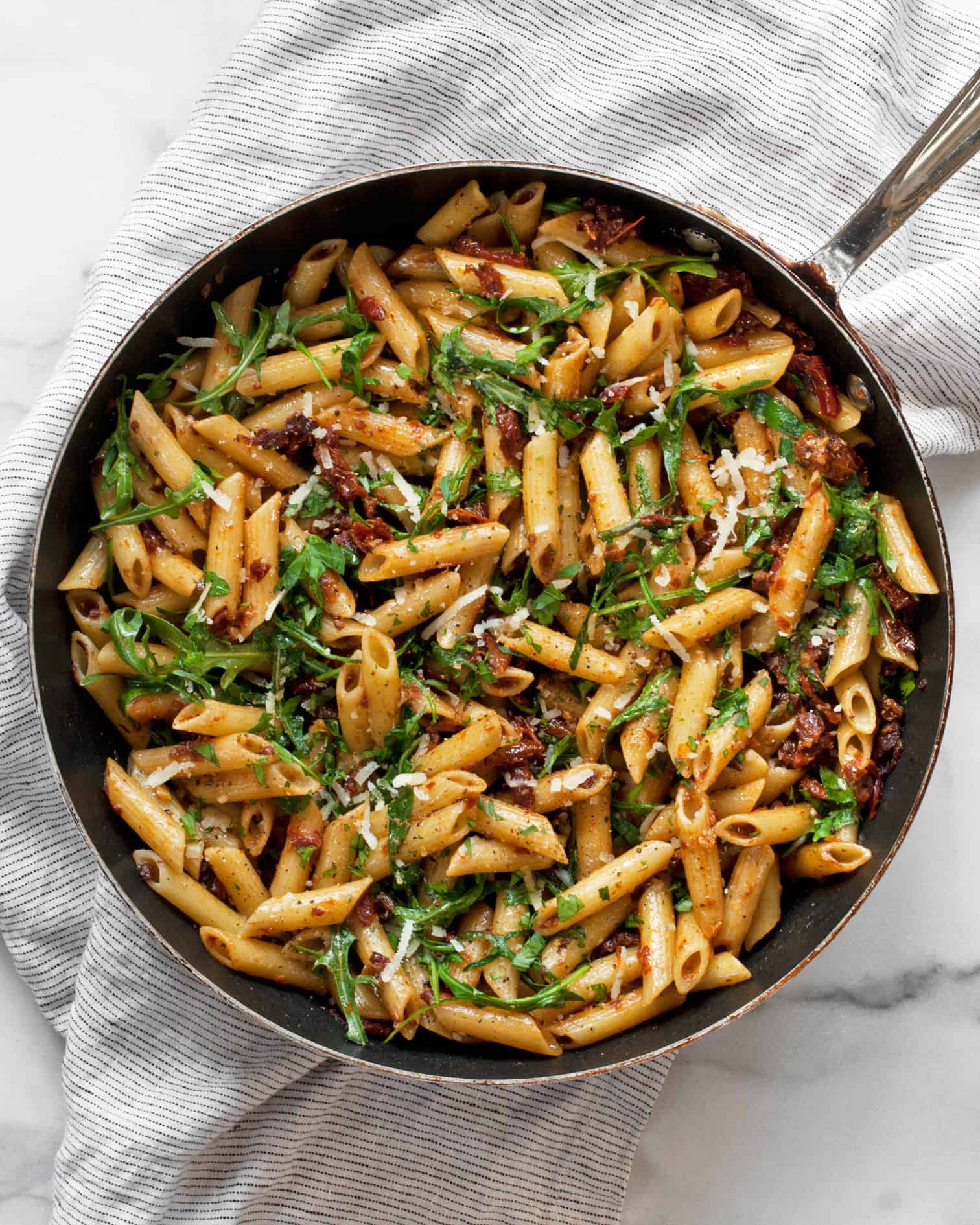 Sun dried tomato pasta with arugula in a skillet