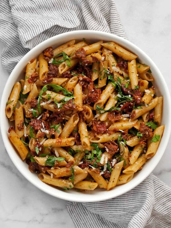 Pasta with sun dried tomatoes and arugula in a bowl