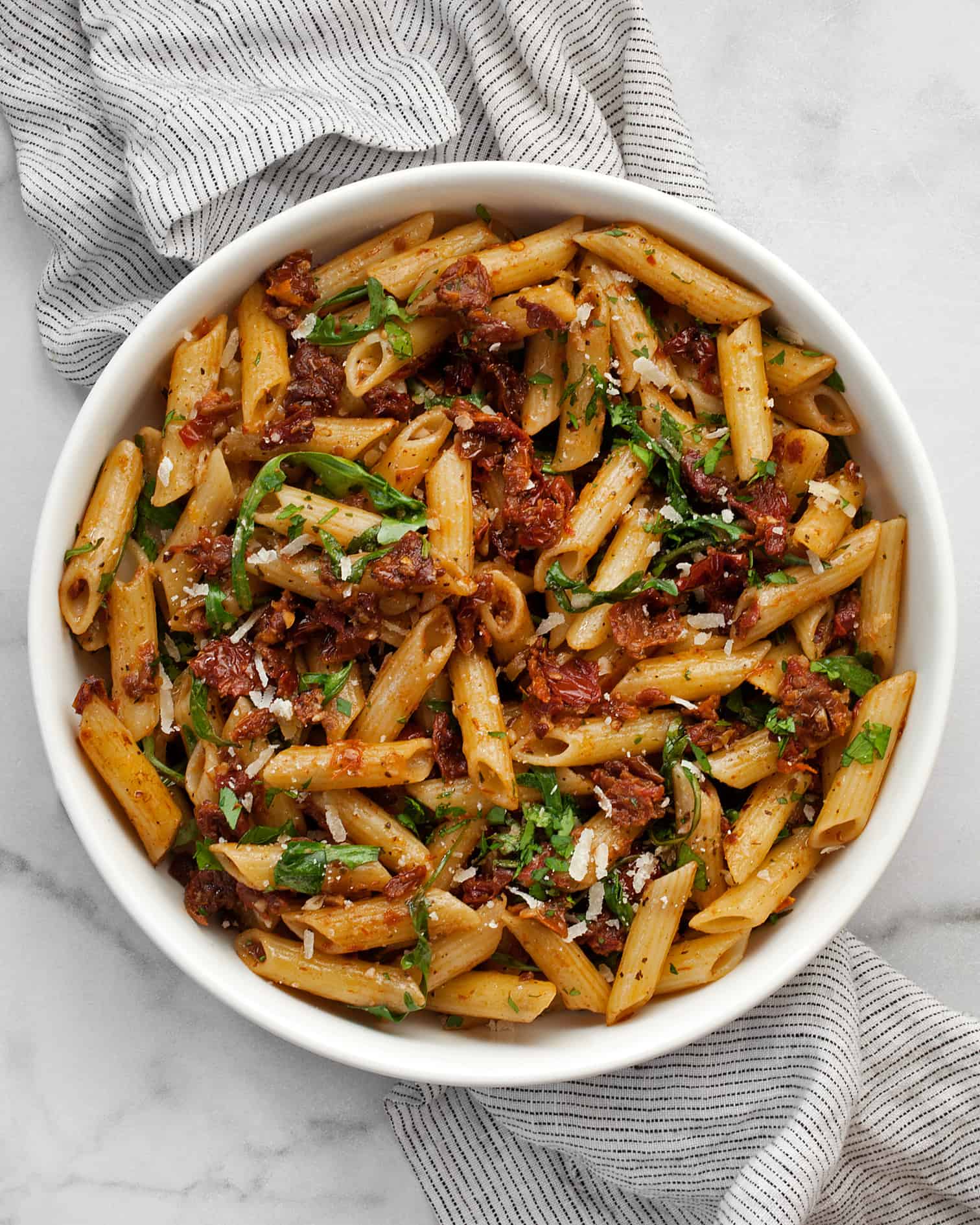 Pasta with sun dried tomatoes and arugula in a bowl