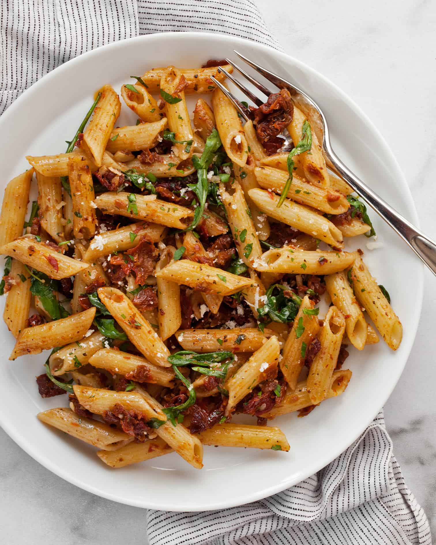 Sun dried tomato penne on a plate with a fork