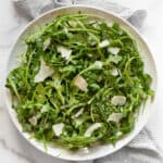 Arugula salad with lemon vinaigrette on a plate.