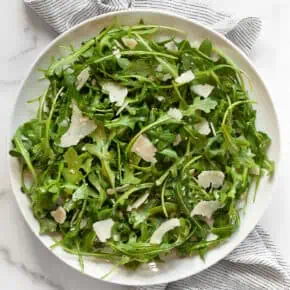 Arugula salad with lemon vinaigrette on a plate.