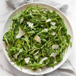 Arugula salad with lemon vinaigrette on a plate.
