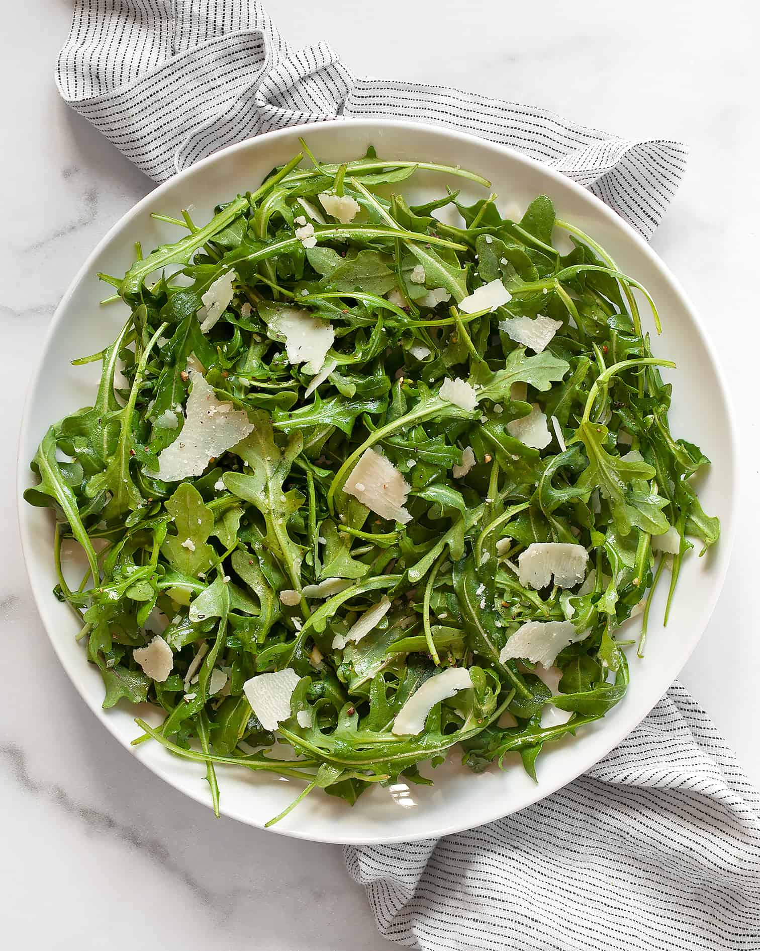 Arugula salad with lemon vinaigrette on a plate.