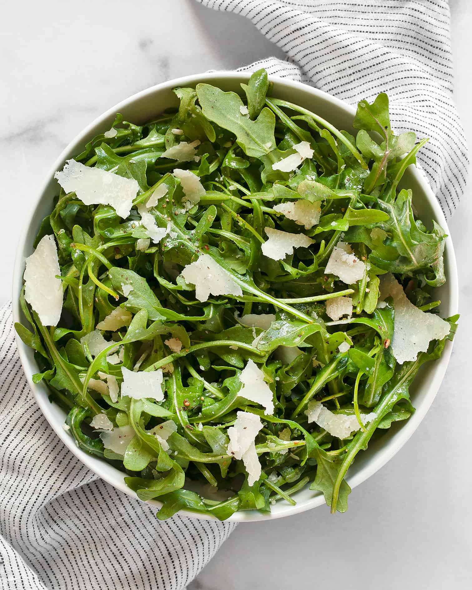 Arugula salad with lemon vinaigrette and Parmesan in a bowl.