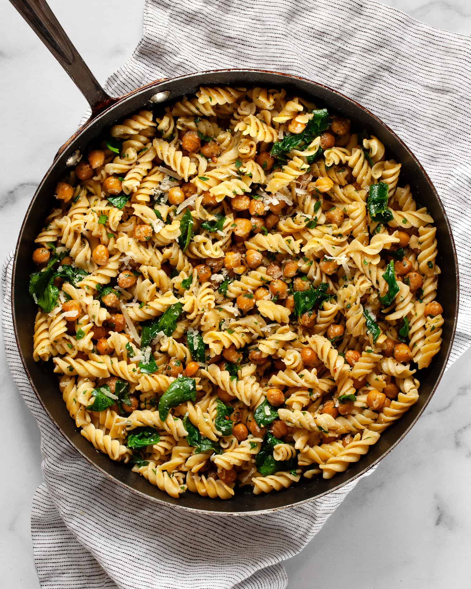 Chickpea pasta with spinach in a skillet.
