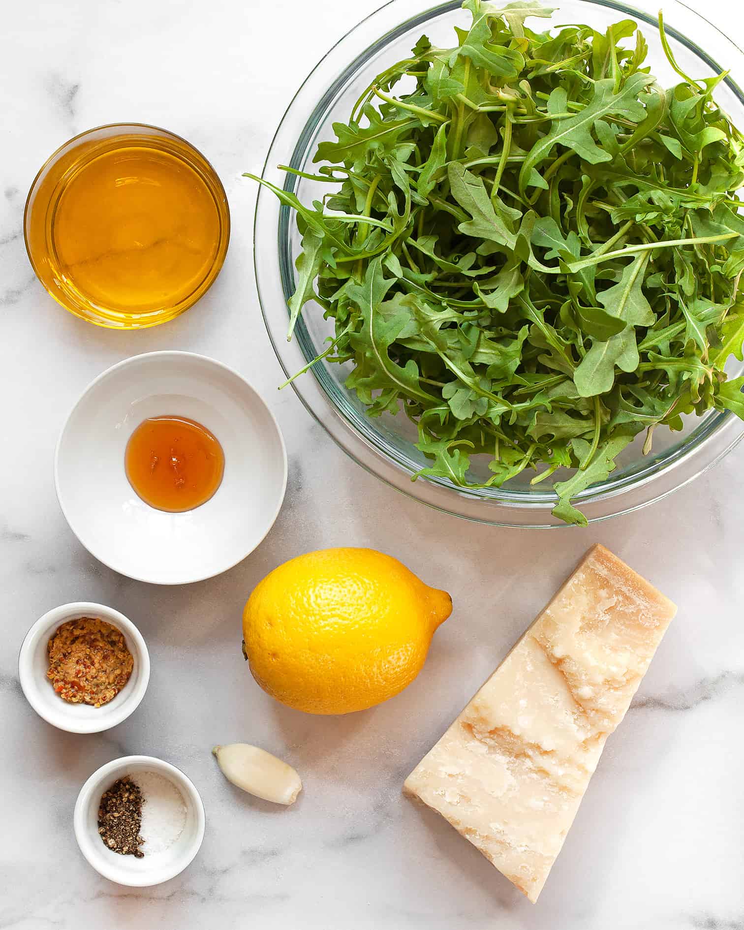 Ingredients including arugula, lemon, parmesan, olive oil, honey, garlic and mustard