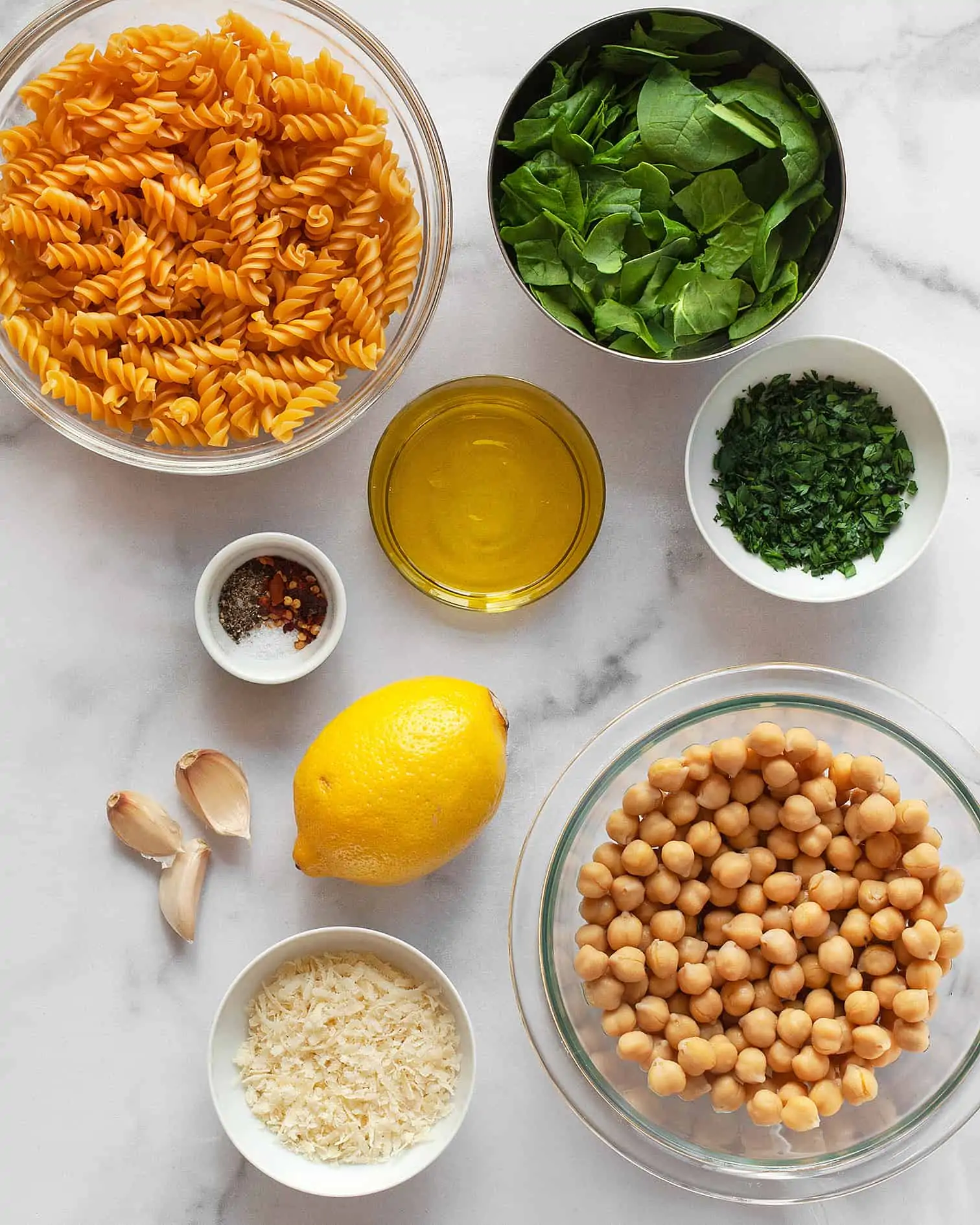 Ingredients including rotini pasta, lemon, spinach, garlic, chickpeas and cheese