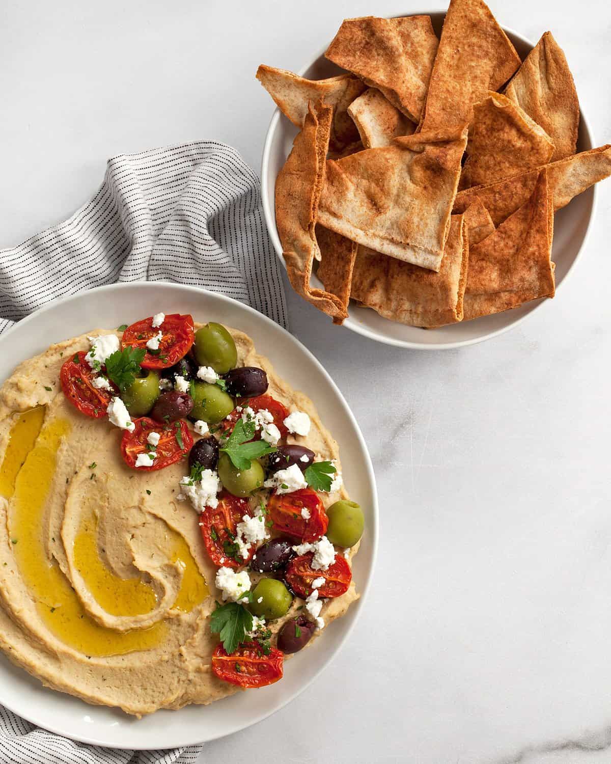 Roasted garlic hummus on a plate served with pita chips.
