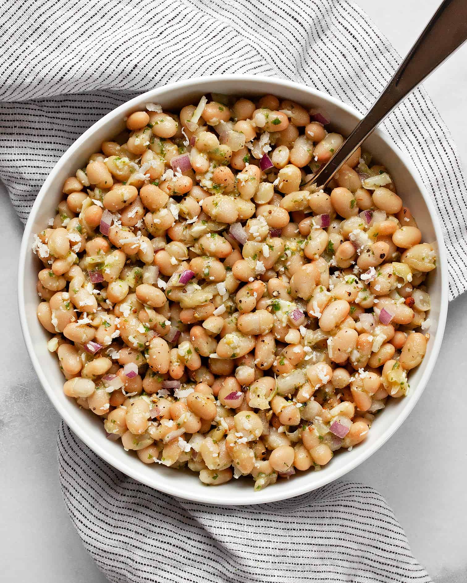 White bean salad in a bowl with a spoon.