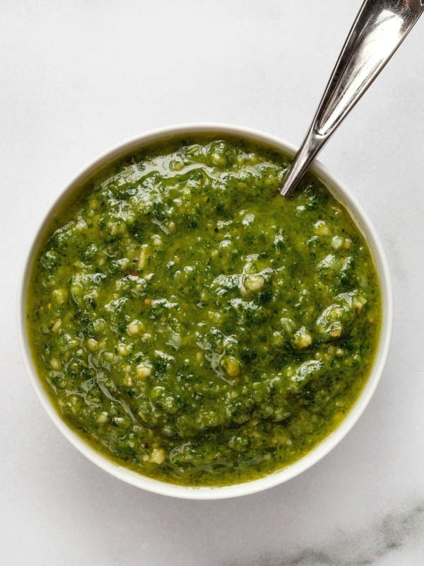 Basil pesto in a small bowl with a spoon