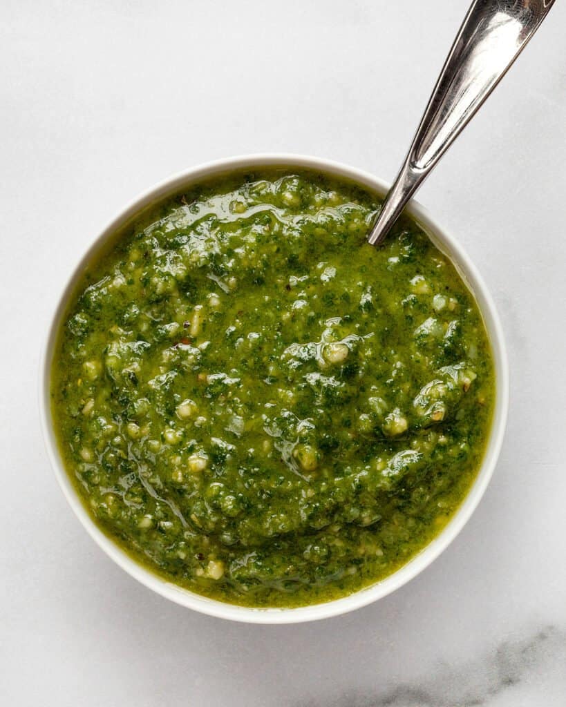 Basil pesto in a small bowl with a spoon