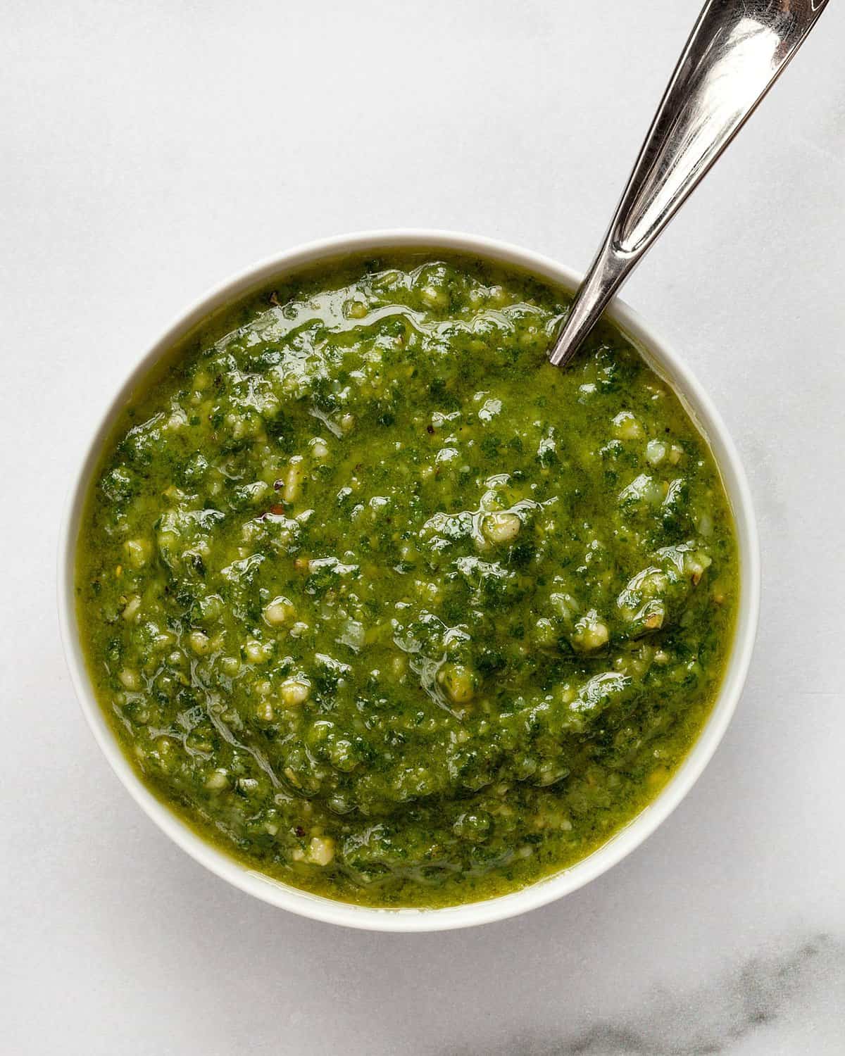 Basil pesto in a small bowl with a spoon