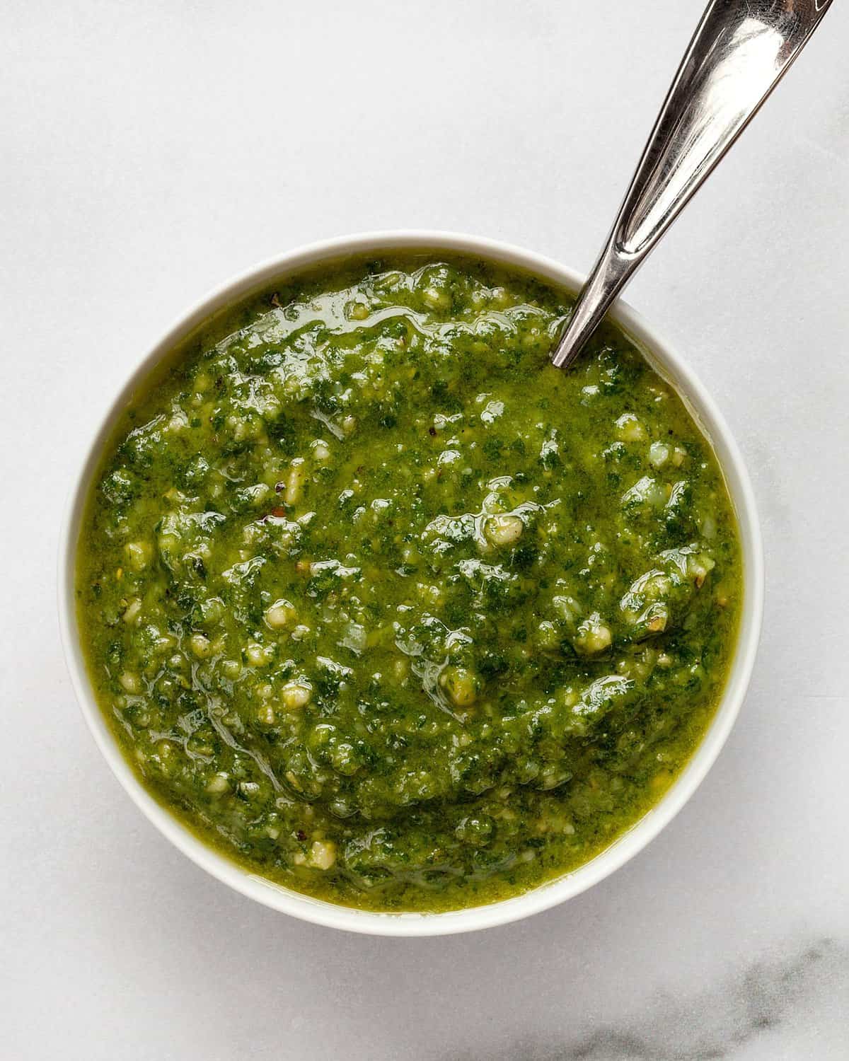 Basil pesto in a small bowl with a spoon