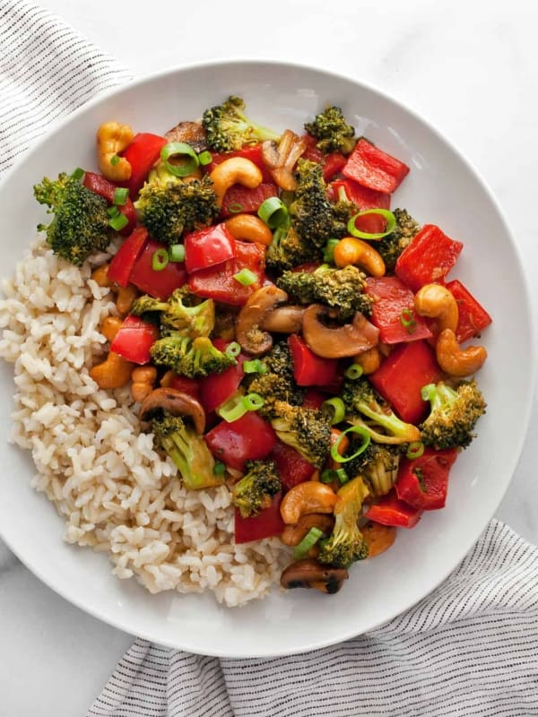 Veggie stir-fry with cashews and rice on a plate.