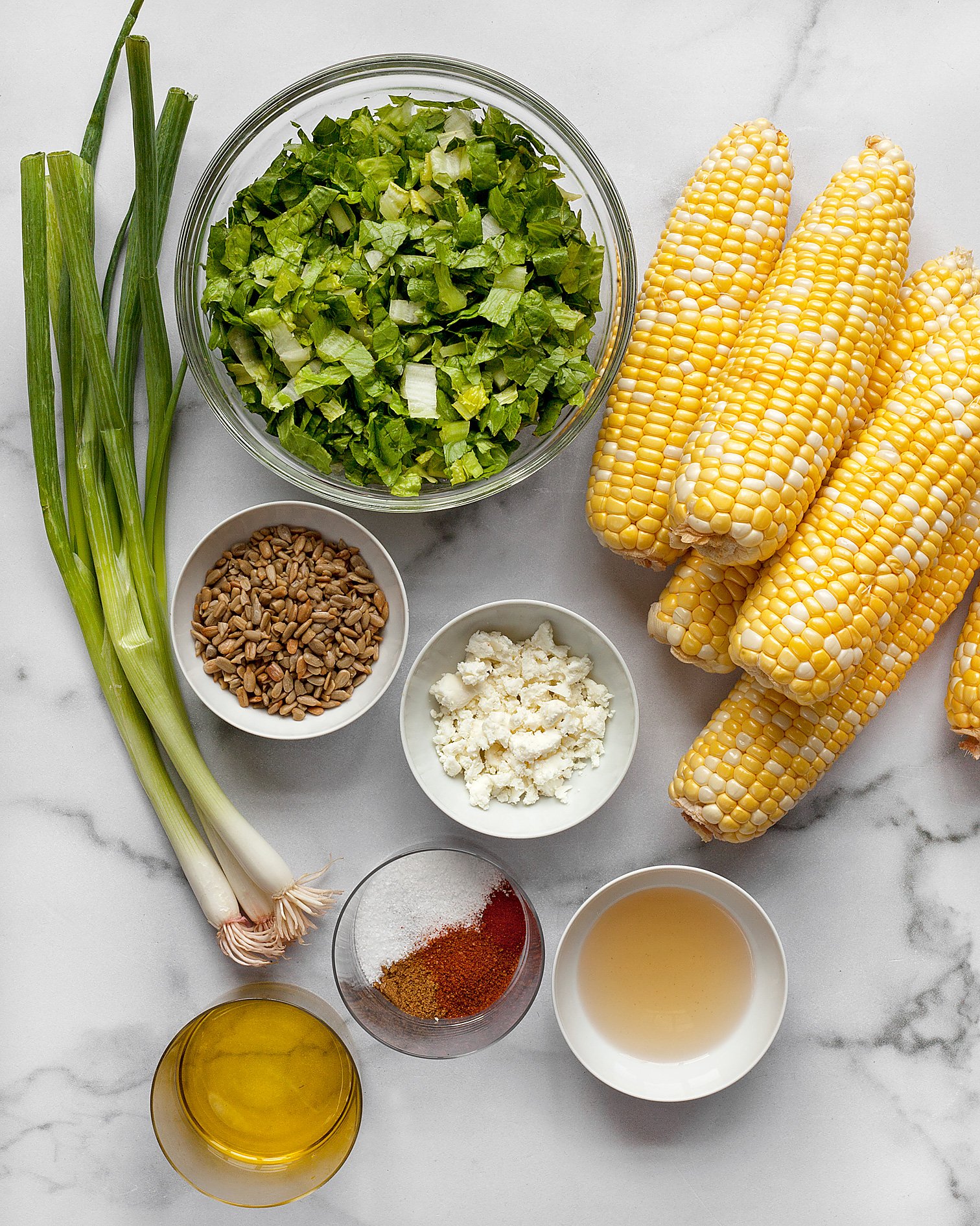 Ingredients including corn, romaine, scallions, feta and spices and oil.