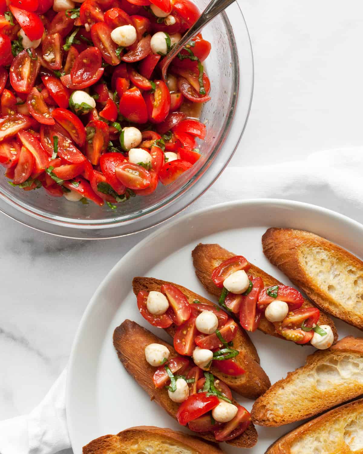 Tomato bruschetta in a bowl with toasted bread on a plate.