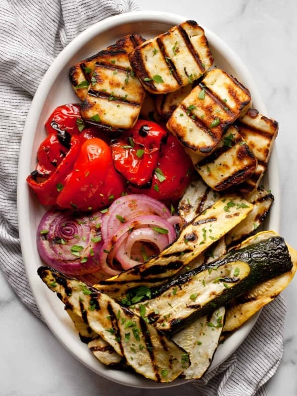 Grilled halloumi with grilled vegetables on an oval serving dish.