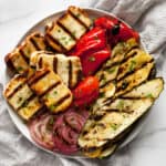 Grilled zucchini, squash, peppers and onions with grilled halloumi on a plate.