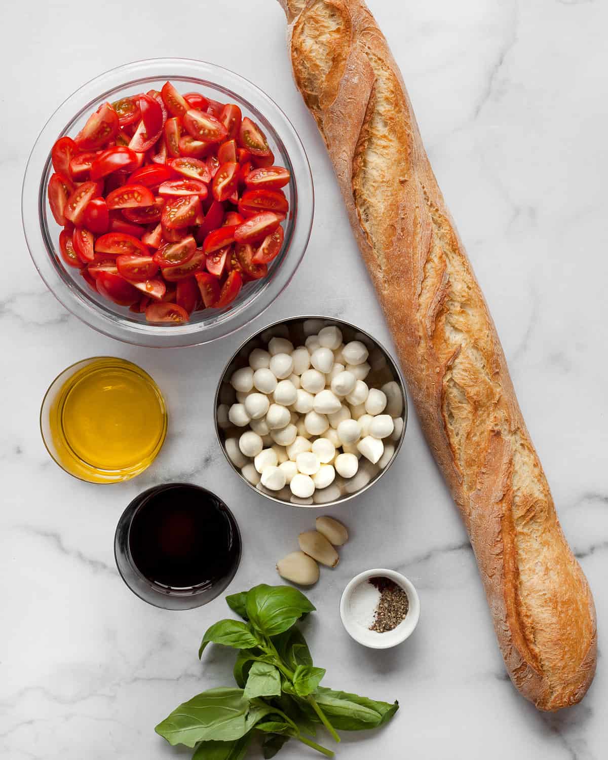 Ingredients including fresh mozzarella, tomatoes, olive oil, vinegar, bread and basil