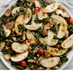 Kale salad with apples and grapes on a plate.