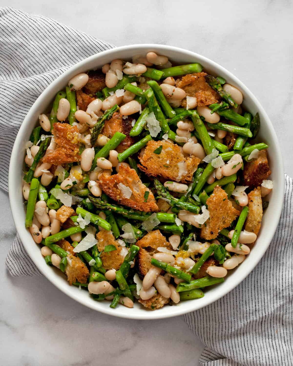 Asparagus salad with cannellini beans and croutons in a bowl.