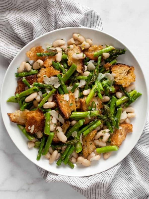 Asparagus salad with cannellini beans and croutons on a plate.