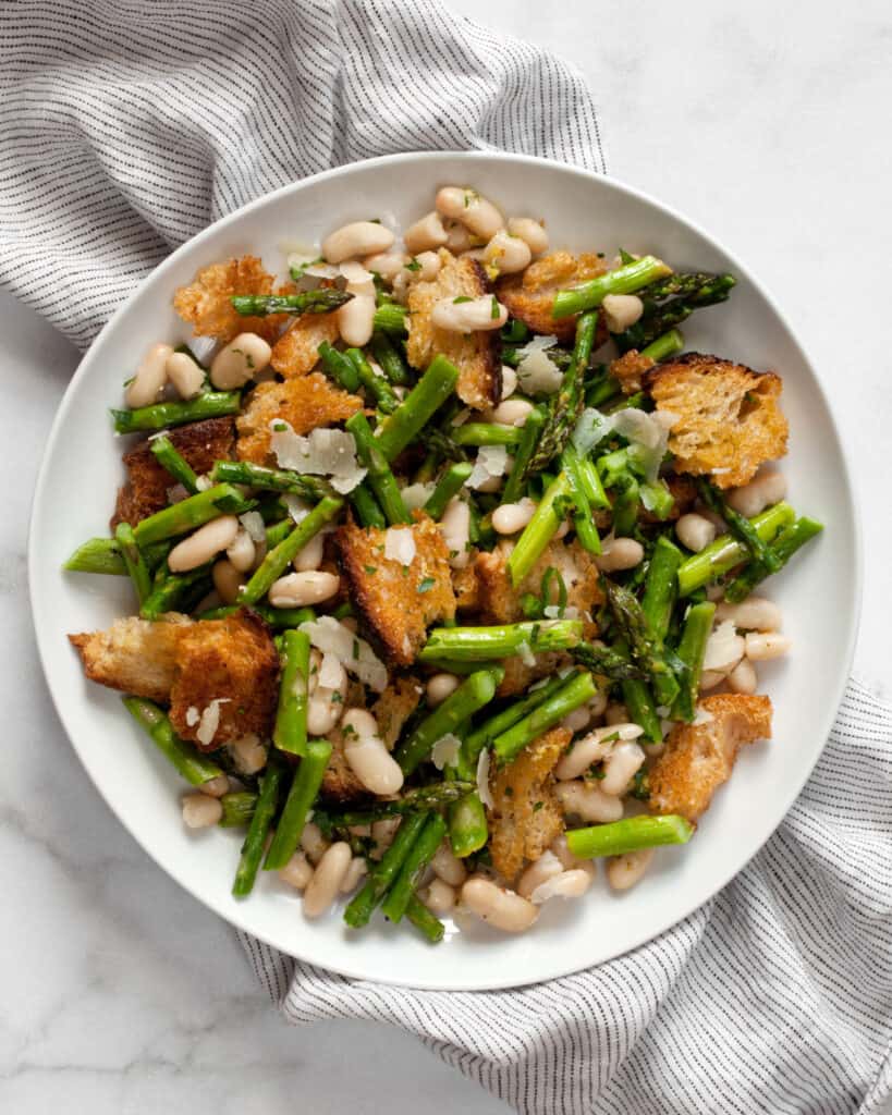 Asparagus salad with cannellini beans and croutons on a plate.