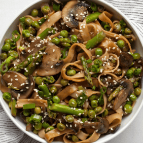 Udon noodle stir-fry with asparagus, mushrooms and peas in a bowl.