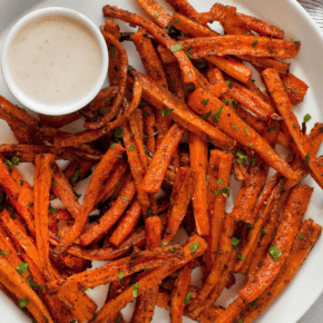 Carrot fries on a plate with tahini dip.