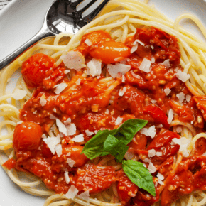 Cherry tomato sauce spooned over spaghetti on a plate.