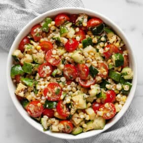 Grilled zucchini salad with corn and tomatoes in abowl.