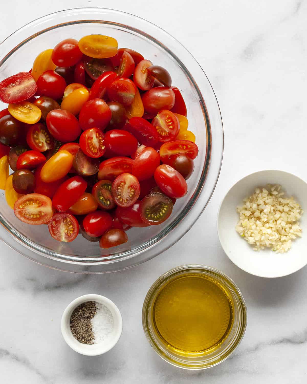 Ingredients including cherry tomatoes, garlic, olive oil, salt and pepper.