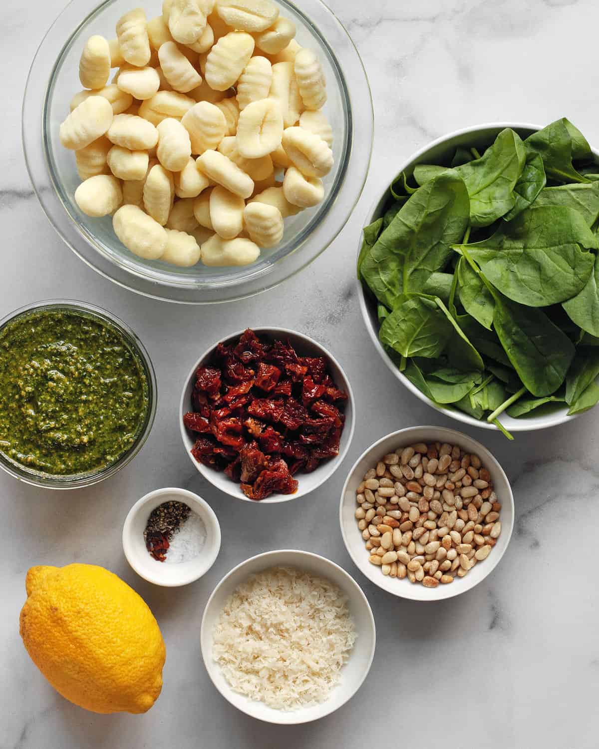 Ingredients including gnocchi, pesto, sun dried tomatoes, spinach, pine nuts, Parmesan, lemon