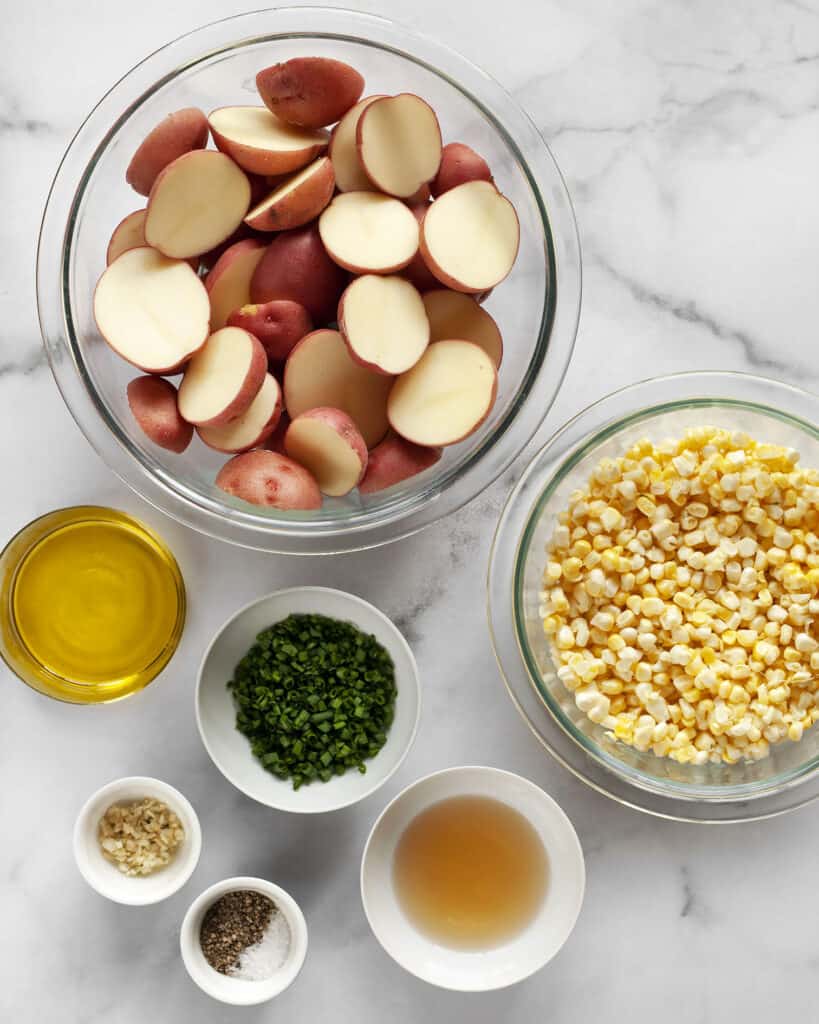 Ingredients including red potatoes, corn, chives, olive oil, garlic, vinegar, salt and pepper.