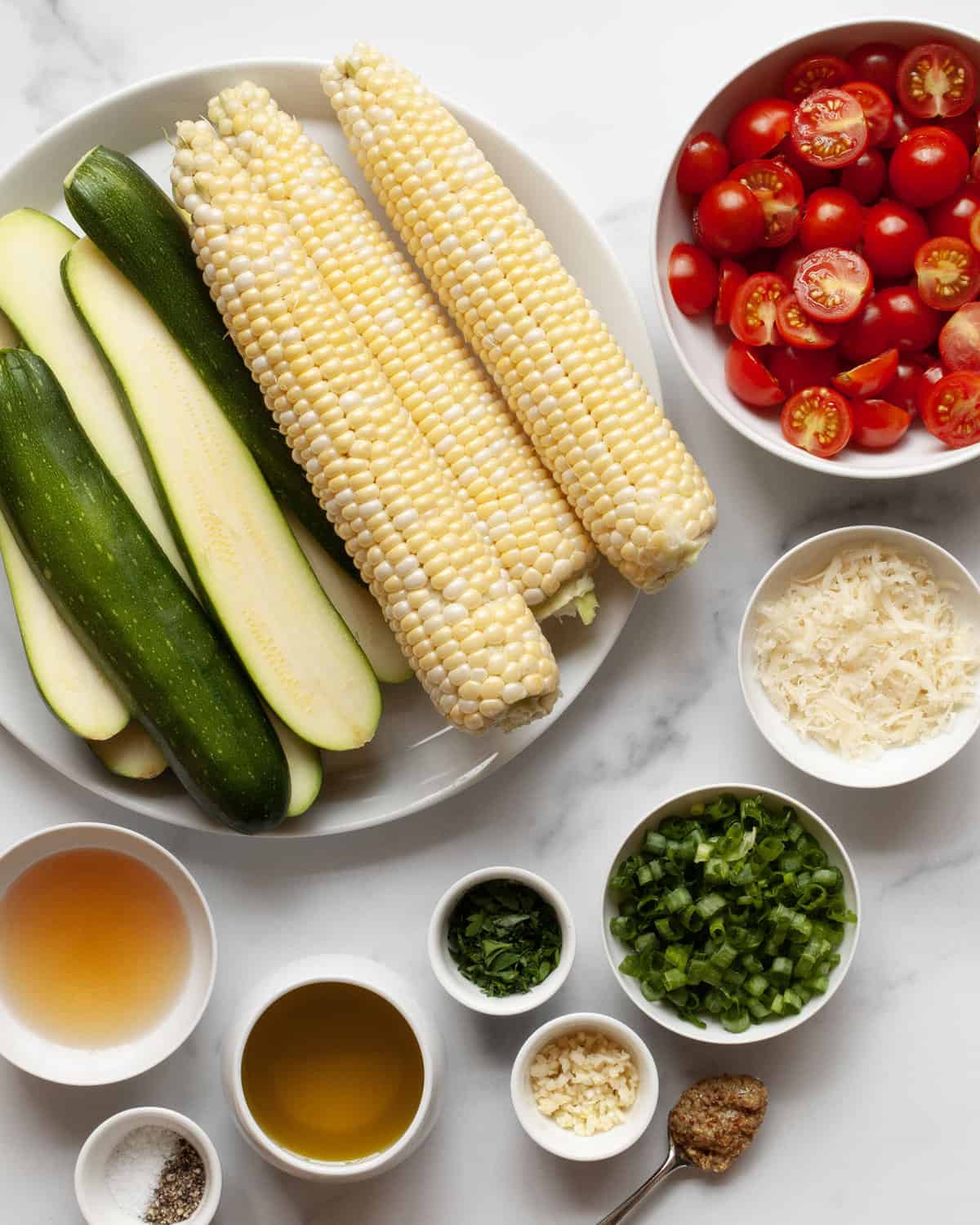 Ingredients for salad including zucchini, corn, tomatoes, scallions, parsley, parmesan, garlic, oil, vinegar and mustard.