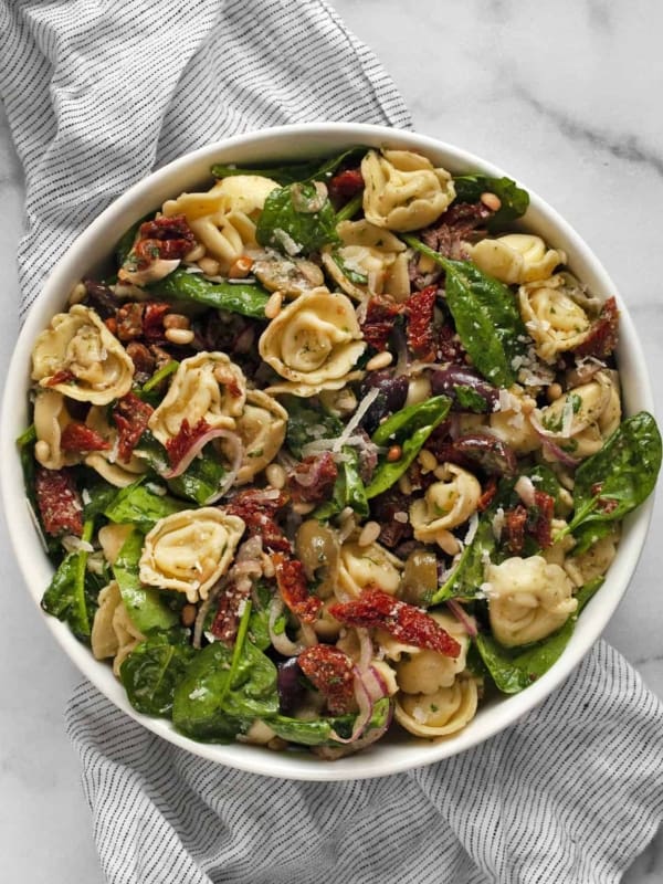 Pasta salad with tortellini, sun dried tomatoes, olives and spinach.