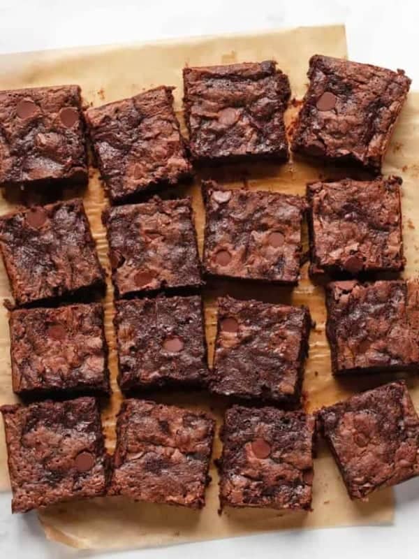 Brownies cut and in rows on parchment paper.