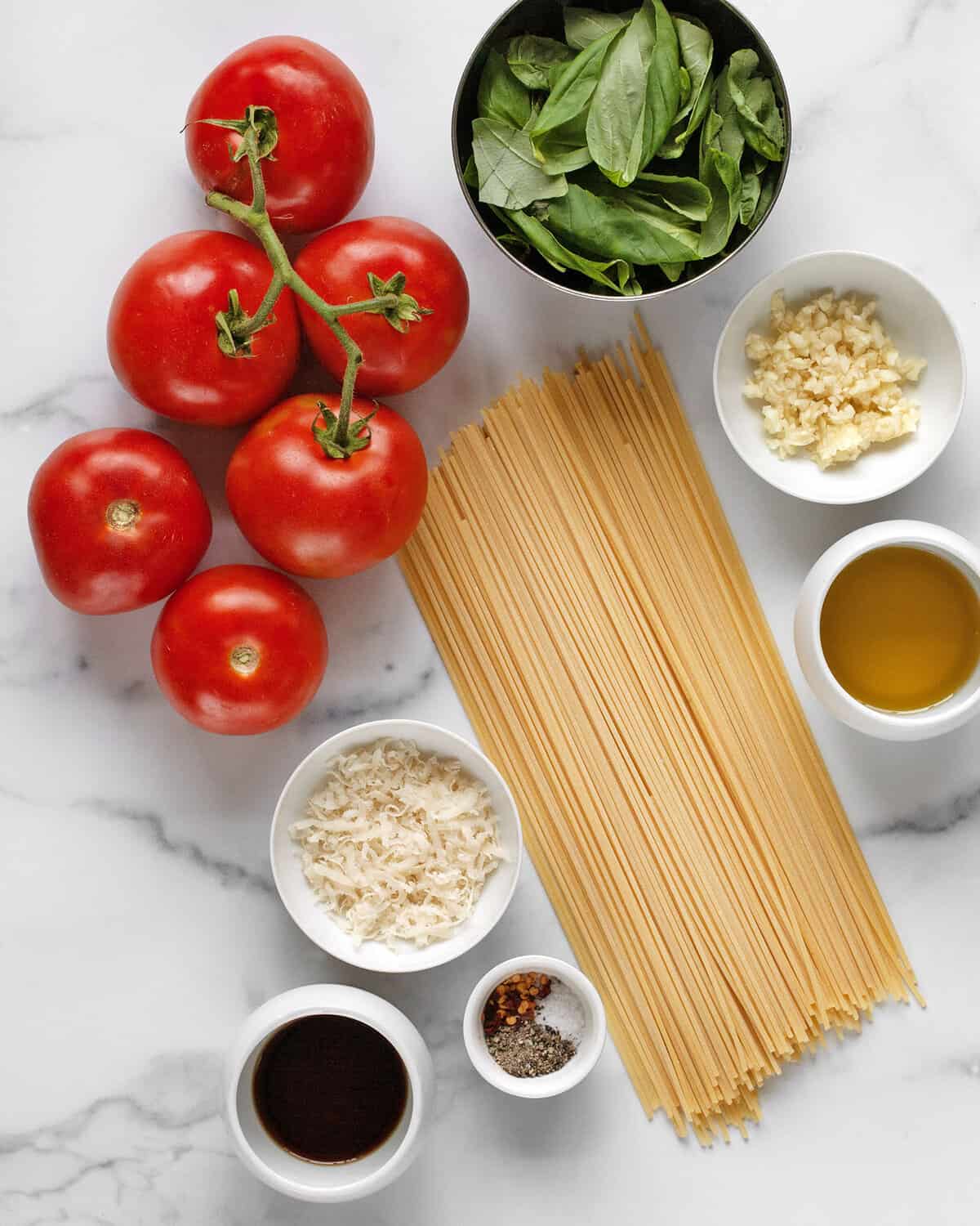 Ingredients including tomatoes, basil, spaghetti, garlic, basil, parmesan, balsamic vinegar, salt and pepper.