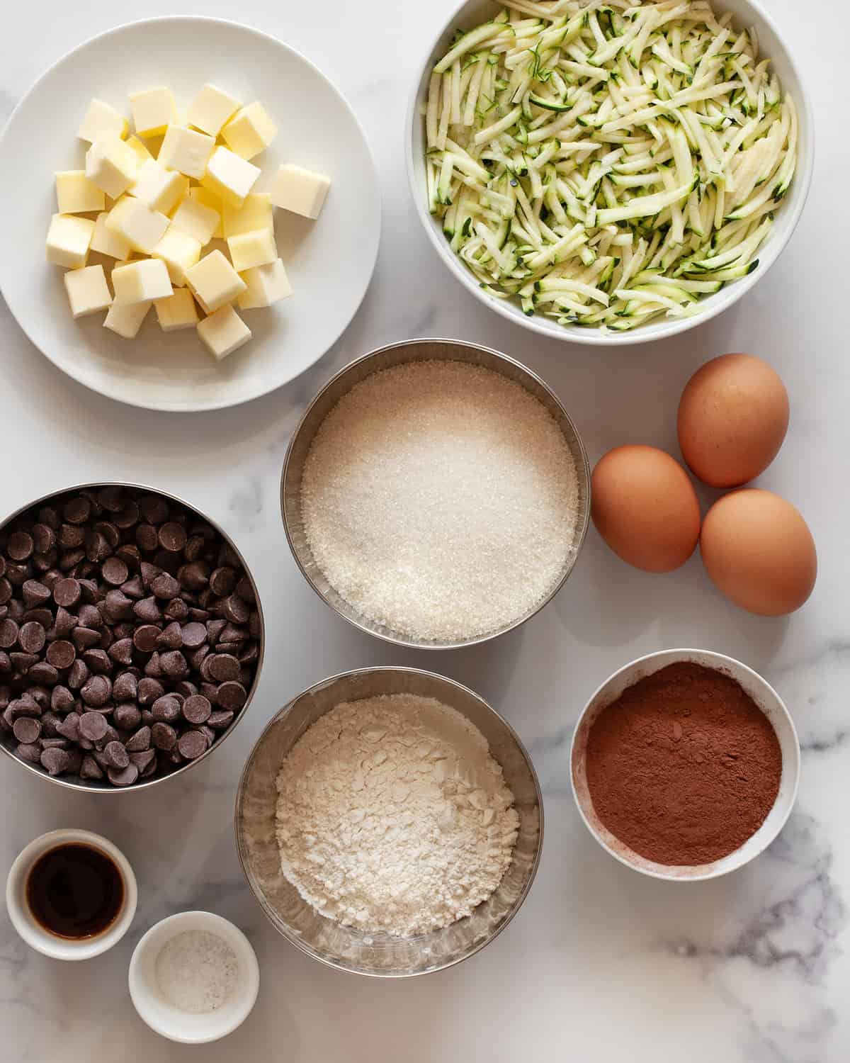 Ingredients including chocolate, shredded zucchini, butter, sugar, eggs, cocoa powder and salt.