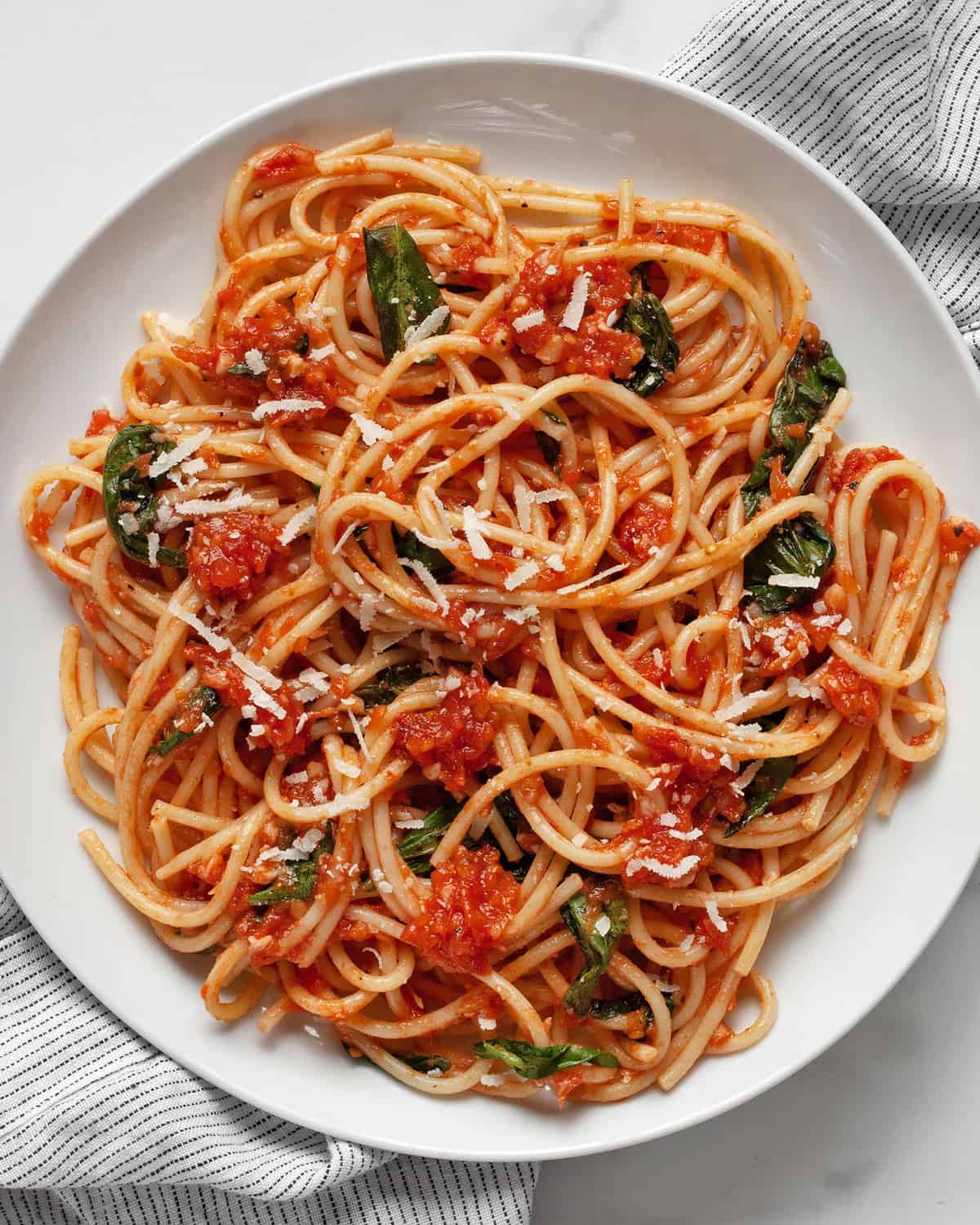 Pasta with fresh tomato sauce and basil on a plate.