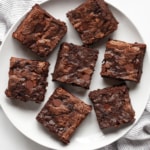 Seven zucchini brownies on a plate.