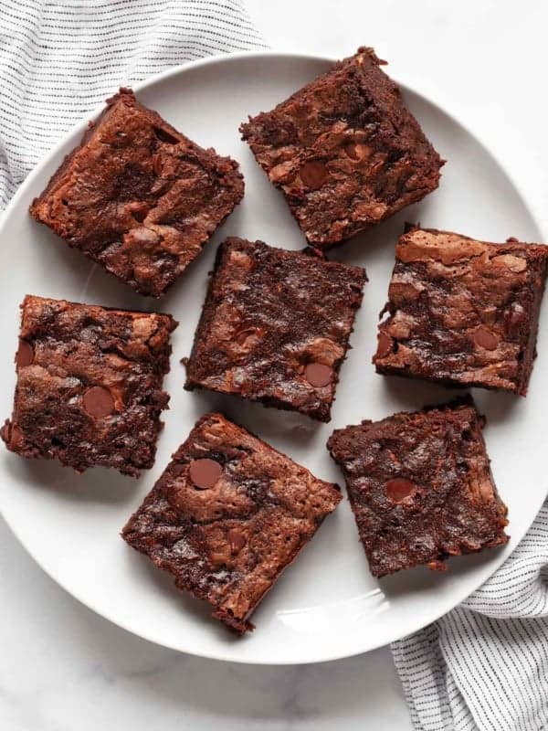 Seven zucchini brownies on a plate.