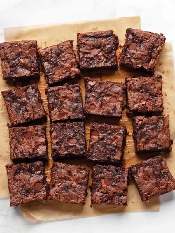 Brownies cut and in rows on parchment paper.