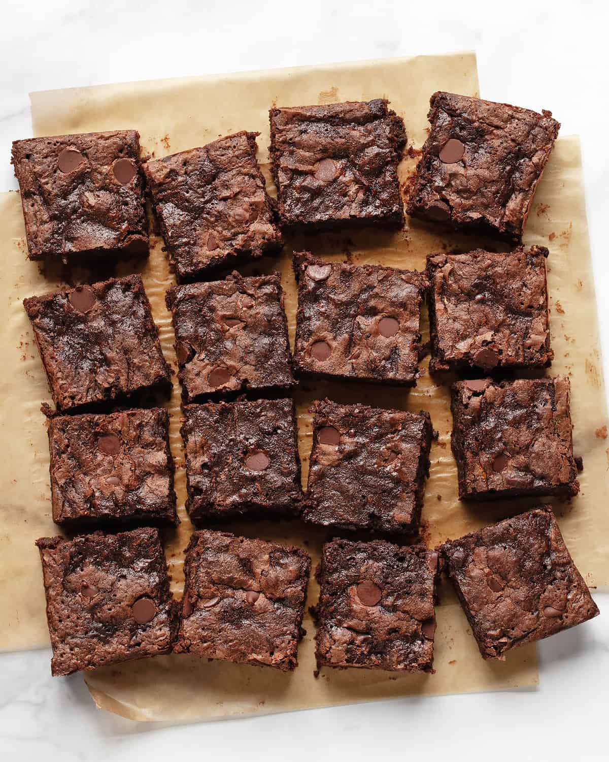 Brownies cut and in rows on parchment paper.