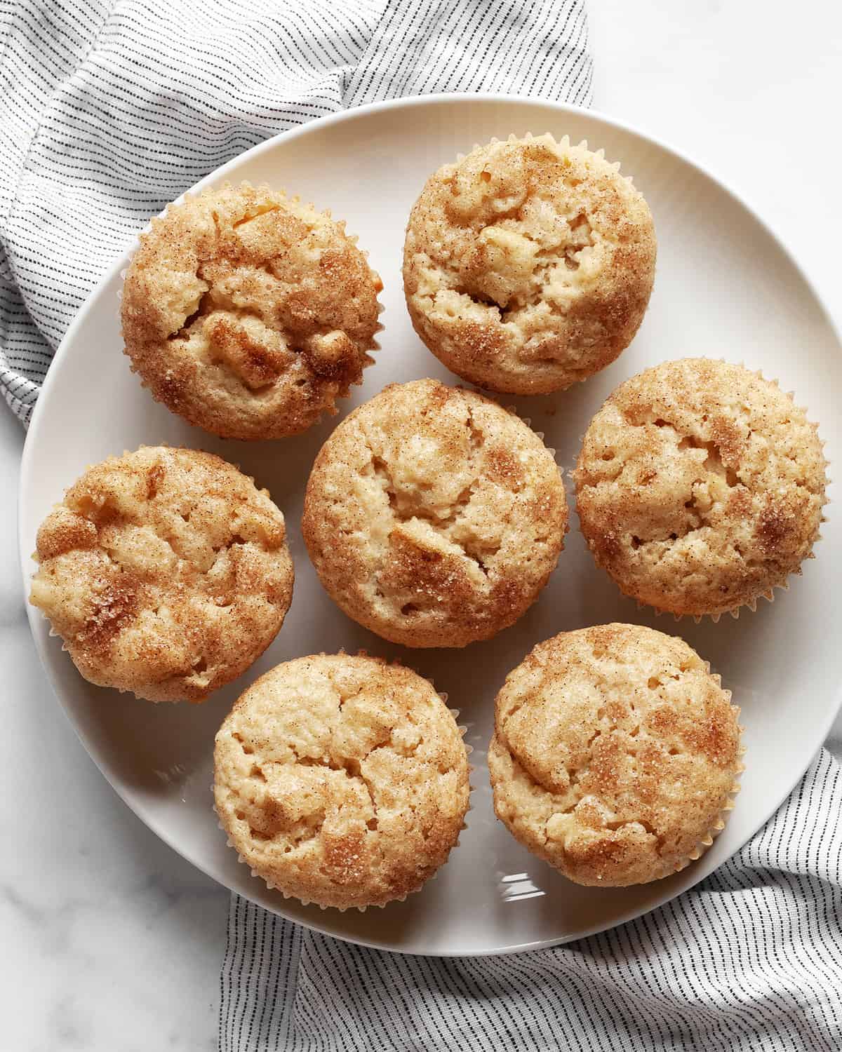 Seven apple cinnamon muffins on a plate.