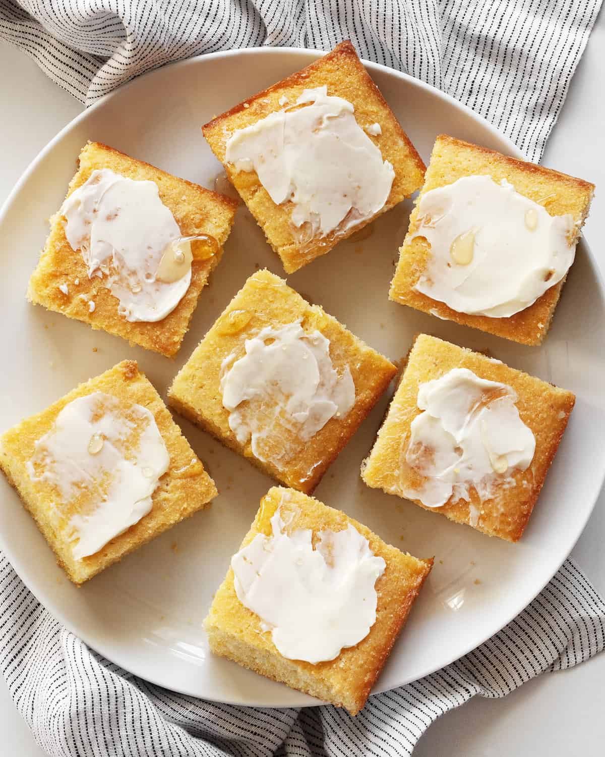 Cornbread cut into squares with the tops spread with butter and drizzled with honey.