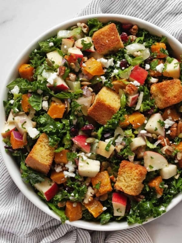 Salad with roasted butternut squash, apples, kale and romaine in a bowl.