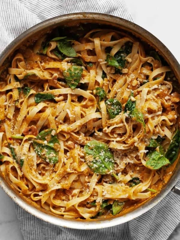 Pasta with pumpkin sauce, spinach and parmesan in a pan.