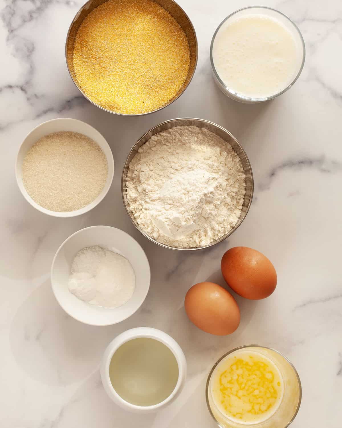 Ingredients including cornmeal, flour, sugar, eggs, salt, baking powder, baking soda, oil, buttermilk and melted butter.